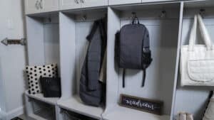 custom mudroom storage featuring a woman's handbag, kid's backpack, shoes, pillows, and more